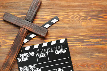 Cross with movie clapper on wooden background. Christmas story concept