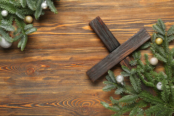 Cross with fir branches and balls on wooden background. Christmas story concept