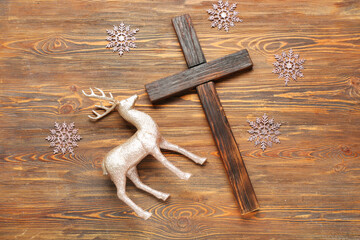 Cross with decorative snowflakes and deer on wooden background. Christmas story concept