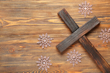 Cross with decorative snowflakes on wooden background. Christmas story concept