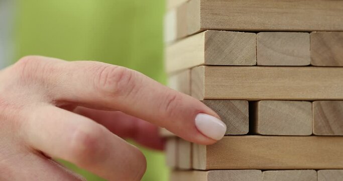 Tower of wooden blocks and person hand takes one block