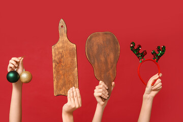 Female hands with wooden cutting boards, Christmas balls and reindeer headband on red background