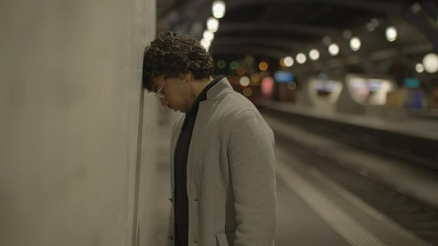 Young Man With Black Curly Hair Waiting Lonely at Train Station at Night