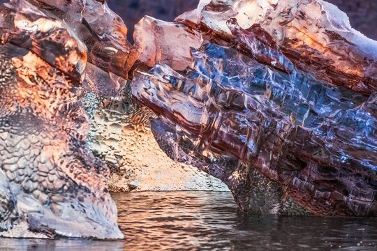 Colorful iceberg in a unique abstract shape in the beautiful sunrise light of the Arctic. Formed over years in a glacier of the Svalbard Archipelago, Norway, Europe