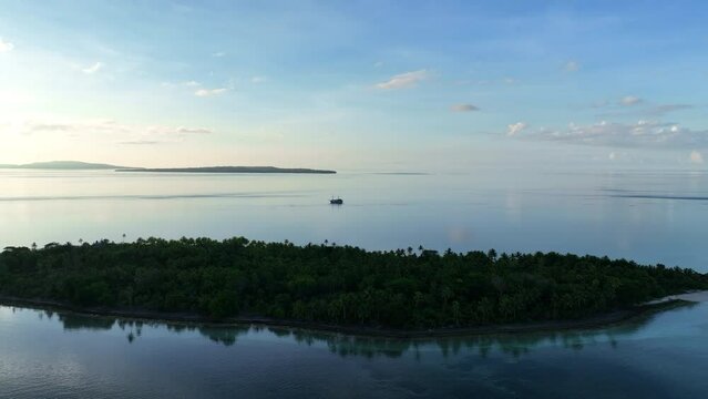 A serene sunrise illuminates the palm-covered, remote island of Koon near Seram, Indonesia. This scenic island's coral reefs, and the surrounding seas, support extraordinary marine biodiversity.