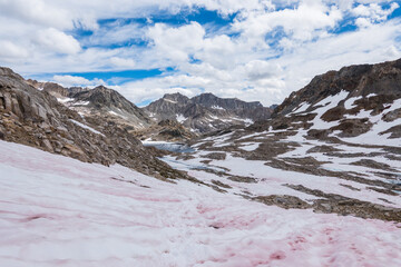 Pink snow on John Muir trail and snow covered mountains in the summer of a wet year