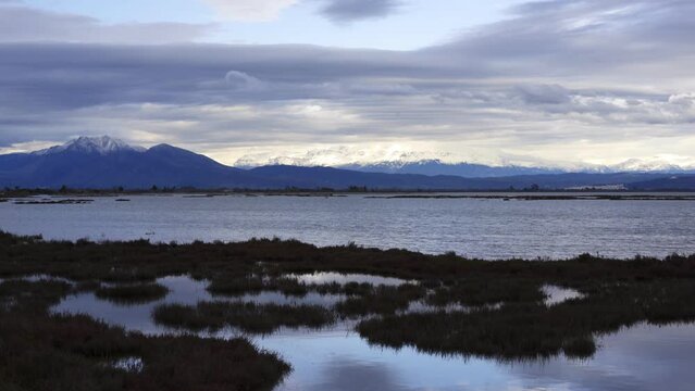 Snow capped mountains in Greece seen from Koronisia with sea on the foreground at sunset, in Greece
