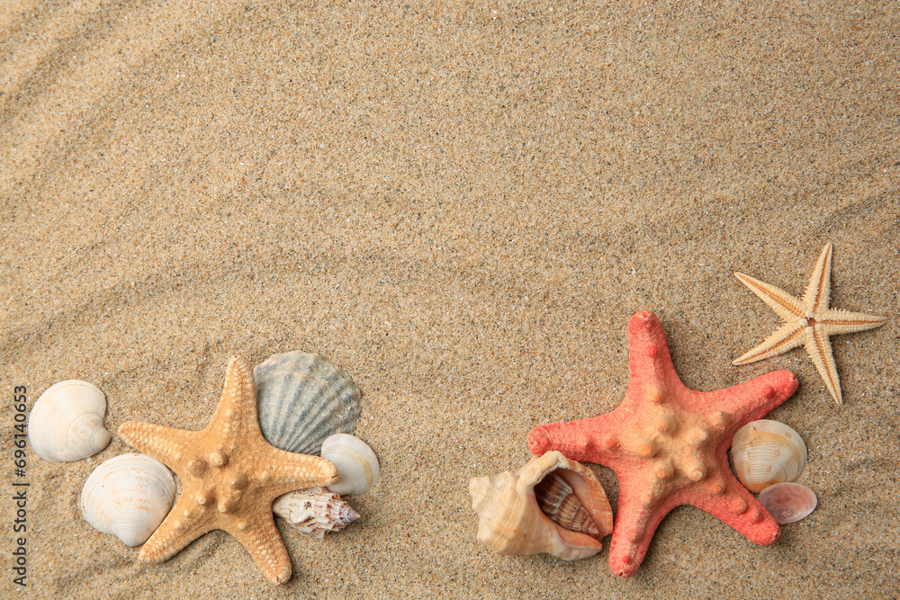 Poster Beautiful sea stars and shells on sand, flat lay. Space for text