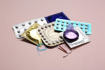Contraceptive pills, condoms and intrauterine device on beige background. Different birth control...