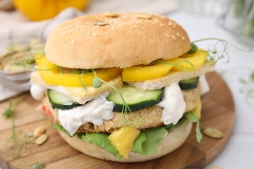 Tasty vegan burger with vegetables, sauce and patty on white table, closeup