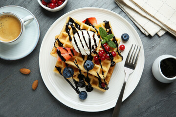 Delicious Belgian waffles with ice cream, berries and chocolate sauce served on grey textured...