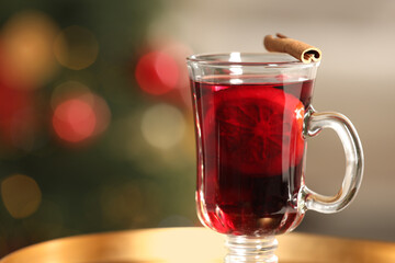 Delicious mulled wine in glass cup against blurred background, closeup. Space for text