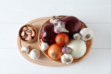 Fresh raw garlic and onions on white table, top view
