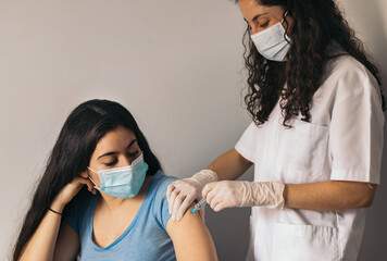 doctor makes vaccination to young woman with surgical mask