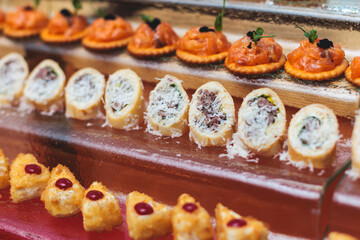 Catering table, beautifully decorated banquet with variety of with different food snacks appetizers on corporate birthday party event or wedding celebration, canape, salad, delicatessen setting