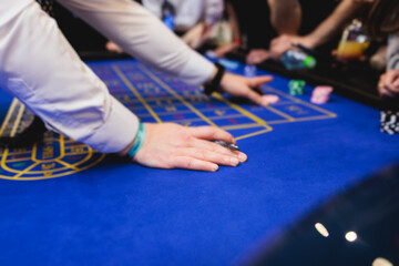 Vibrant casino table with roulette in motion, with casino chips, tokens, the hand of croupier,...