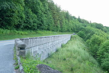 Fototapeta premium a stone automobile traffic bridge cut into the side of a mountain, the single lane, two-way roadway brings traffic over some foothills and through a valley for interstate travel of people and goods