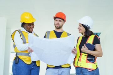 Engineer team discuss and examine about the building plan on blueprint together.