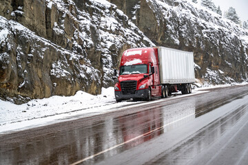 Industrial long haul red big rig semi truck with dry van semi trailer waits out bad weather...