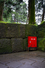 fire extinguisher box on a mossy stone wall along a temple path