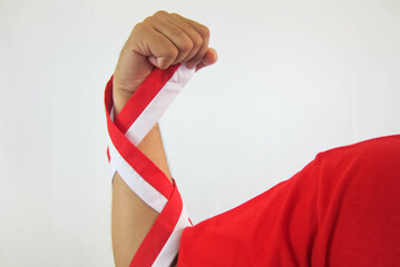 The hands of a man holding a red and white ribbon as a symbol of the Indonesian flag. Isolated on...