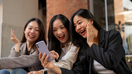Group of surprised young Asian female friends are surprised with an online discount on shopping app
