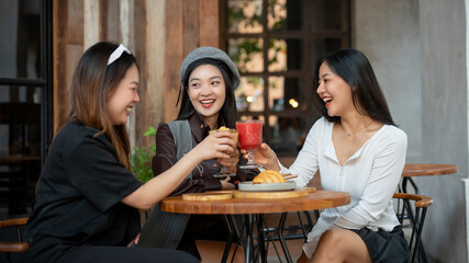 A group of trendy, happy Asian girls are drinking and enjoying talking in a cafe in the city.