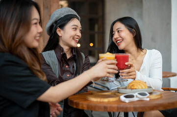 A group of trendy, happy Asian girls are drinking and enjoying talking in a cafe in the city.