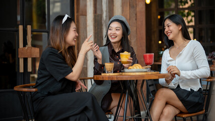A group of trendy, happy Asian girls are drinking and enjoying talking in a cafe in the city.