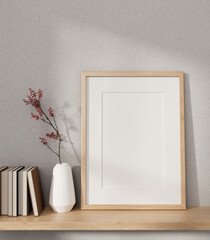A minimal picture frame mockup, books, and a vase on a wooden wall shelf against the white wall.