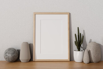 An empty picture frame mockup, ceramic vases, and decorating stuff on a wooden desk.