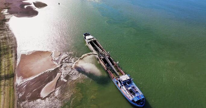 Aerial top shot of a dredger unloading dredged sand on a big river, sunny day