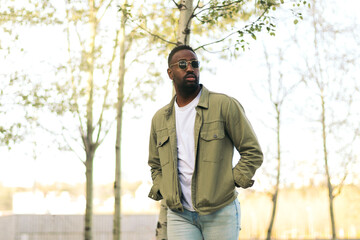 Stylish afro american young man with sunglasses walking in a park