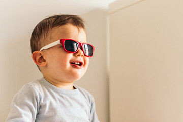 funny baby with sunglasses sitting at home
