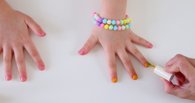 Mother paints her little daughters on the table, beauty ritual