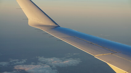 The airplane wing view looked from the flying plane window with the sunset sunlight on it