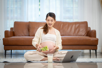 Asian woman who is pregnant Eating vegetable salad at home
