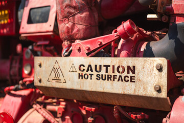 Steel plate "Hot surface" caution sign on the heavy pumping unit machinery for operating in refinery industrial. Industrial safety equipment and symbol object.