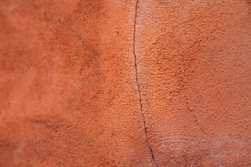 Close-up at orange pastel roughly  concrete wall with cracked line on surface. Background and texture photo.