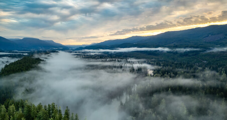 Valley by Mountains and Green Trees covered in fog. Canadian Landscape Nature Aerial