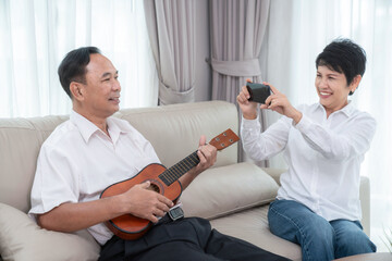 Asian old couple sing a song and play ukulele togather in living