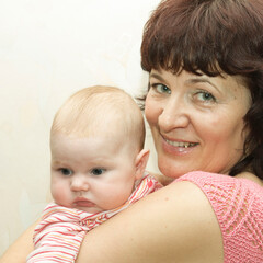 young beautiful grandmother holding her infant granddaughter in her arms