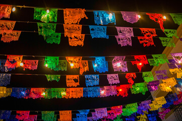 Colorful paper flags or papel picados hang at night with lights in the streets of historic San Jose del Cabo.