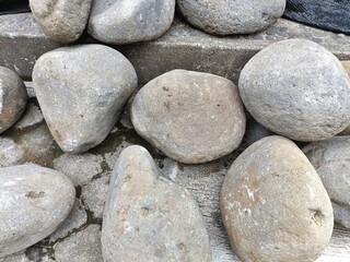 Pile of smooth irregular shaped gray stones natural horizontal background texture