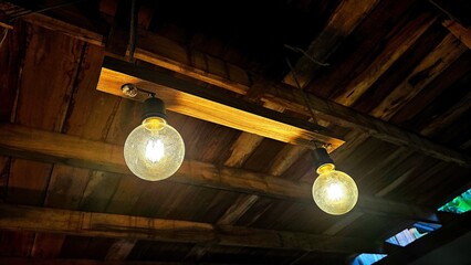 Vintage lamp on the wooden ceiling. Big light bulbs. Classic round ceiling lighting lamp is glowing in the dark room. Antique decorative lamp.