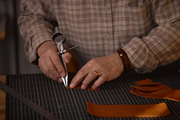 Leather marking process. focus on hands holding Wing Divider, leather Compass, necessary tools for...