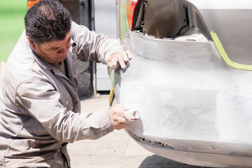 Senior mechanic man repairing the bumper of a car