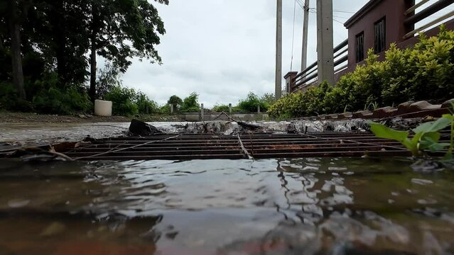 Water flows down through the manhole cover. Rain flows into a sewer system. Water flows into sewer system after a heavy rain