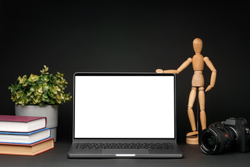 Open laptop with wooden mannequin on table against black background