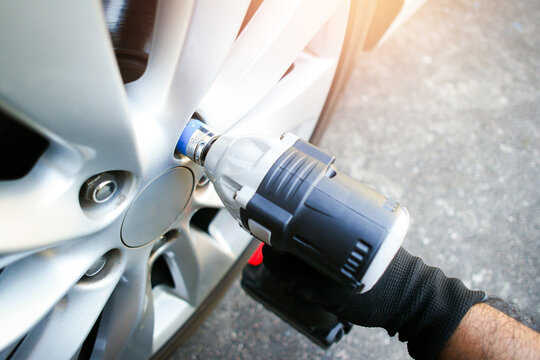 Car mechanics use cordless impact wrenches to remove car wheel nuts , Car miantenance service concept - Powered by Adobe